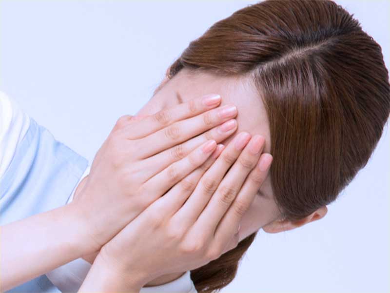 憂鬱で顔を手で覆っている奥さん