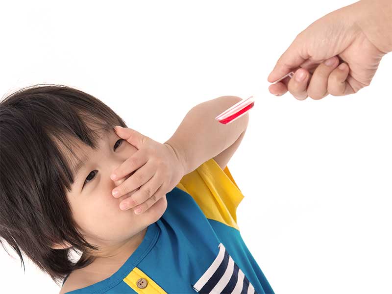 口を手で塞いで薬を飲むのを拒否している赤ちゃん