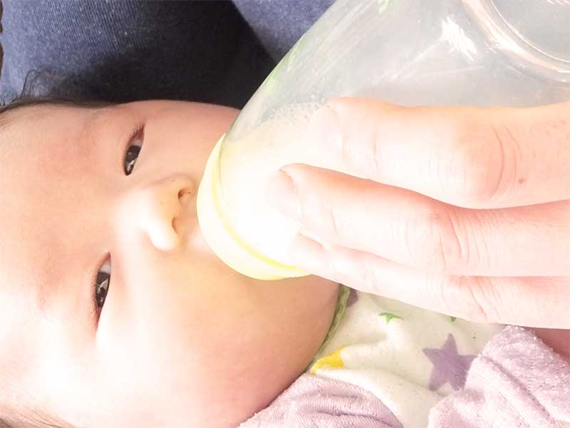 哺乳瓶で母乳を飲んでる赤ちゃん