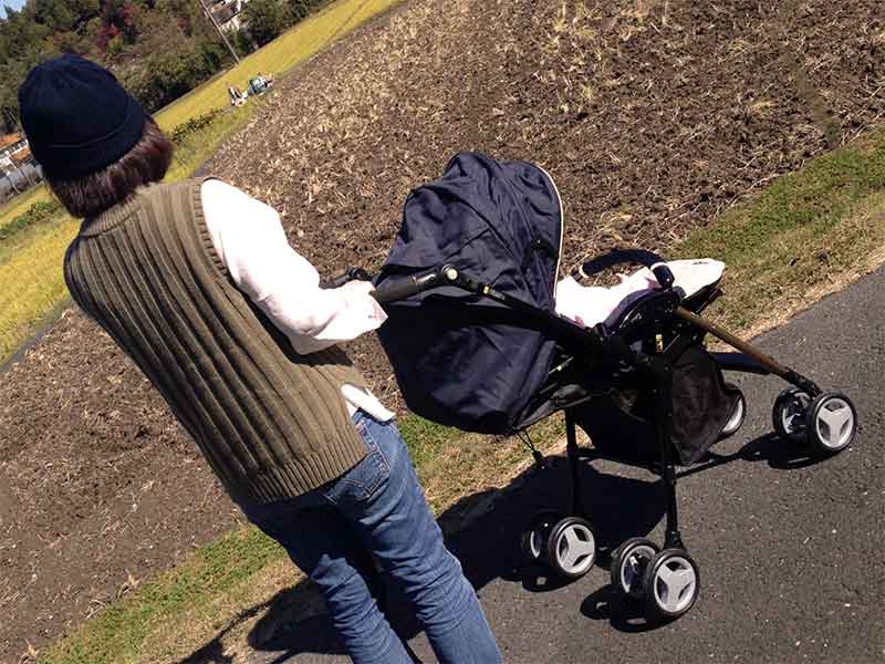 ベビーカーに赤ちゃんを乗せて散歩してるママ