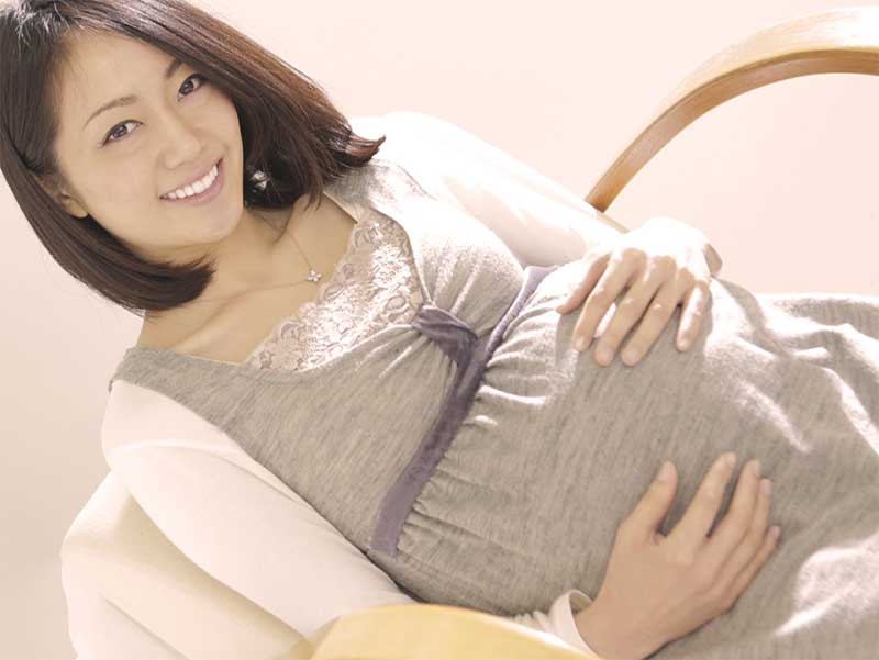椅子に座ってお腹をおさえてる妊婦