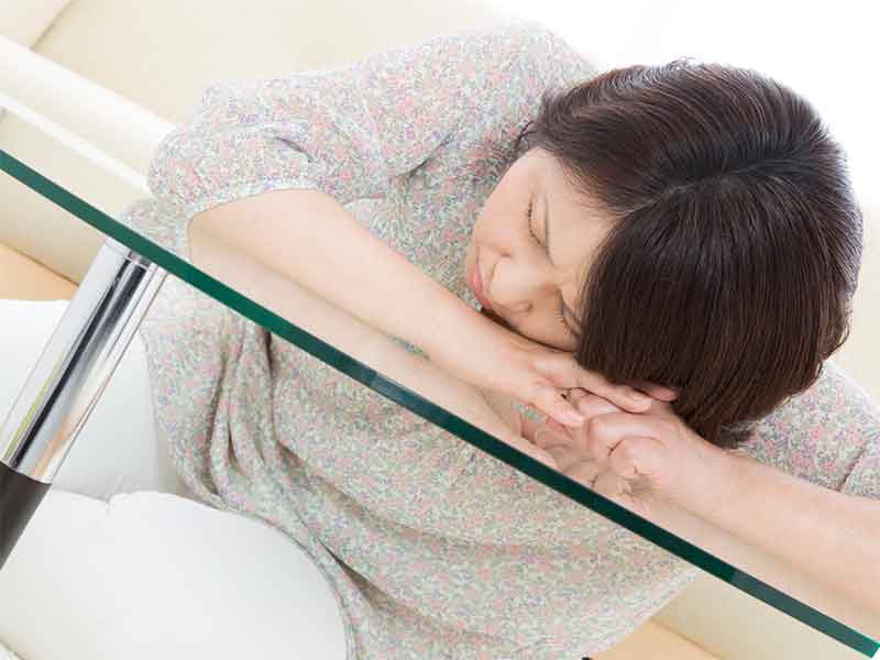 うつでテーブルに突っ伏してる中年女性