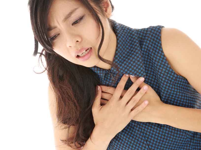 胸に圧迫感を感じておさえてる女性