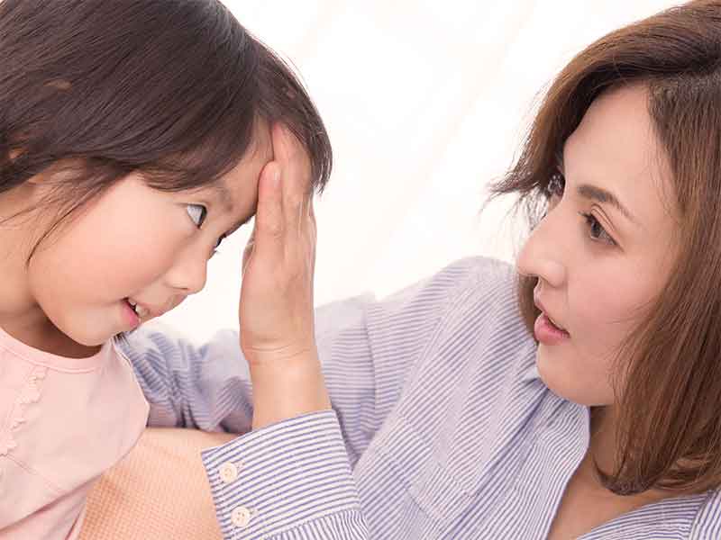 母親におでこを触られてる熱がある子供