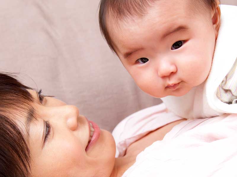 横になっているお母さんの上に赤ちゃんがいる
