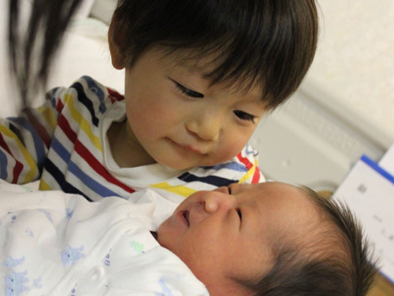お兄ちゃんが生まれたばかりの赤ちゃん兄弟を見ている