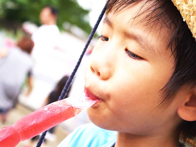 外でアイスを食べてる男の子
