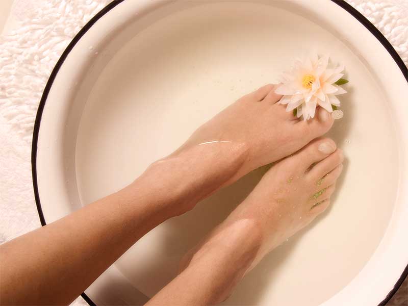 足湯で身体を温めてる女性の足元