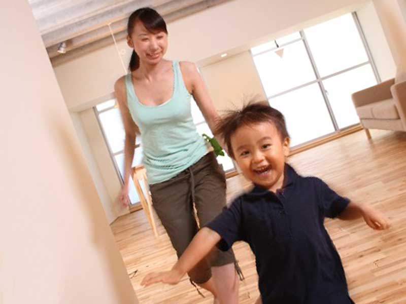 家で走る回る男の子を追うお母さん