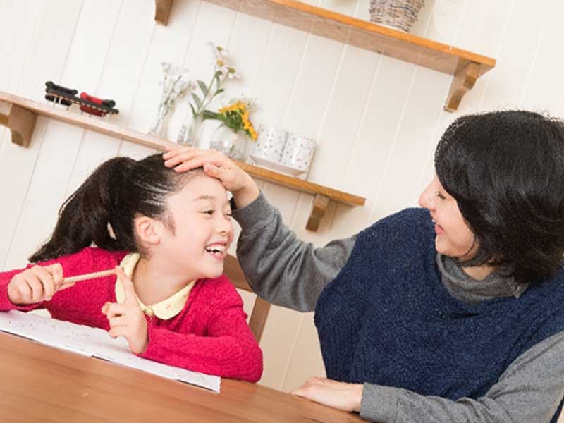 勉強している子供の頭を撫でるお母さん