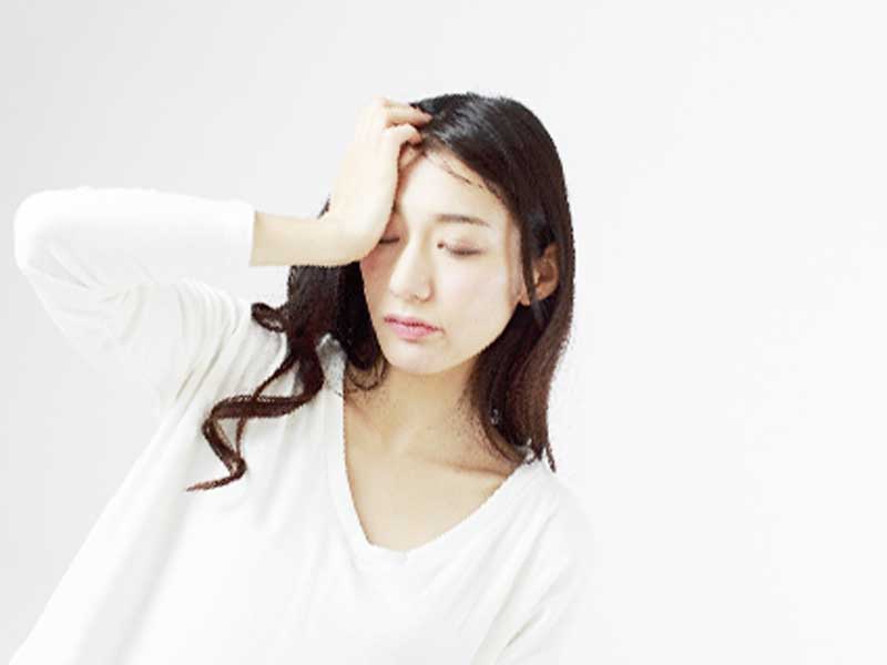 頭痛で頭をおさえてる女性