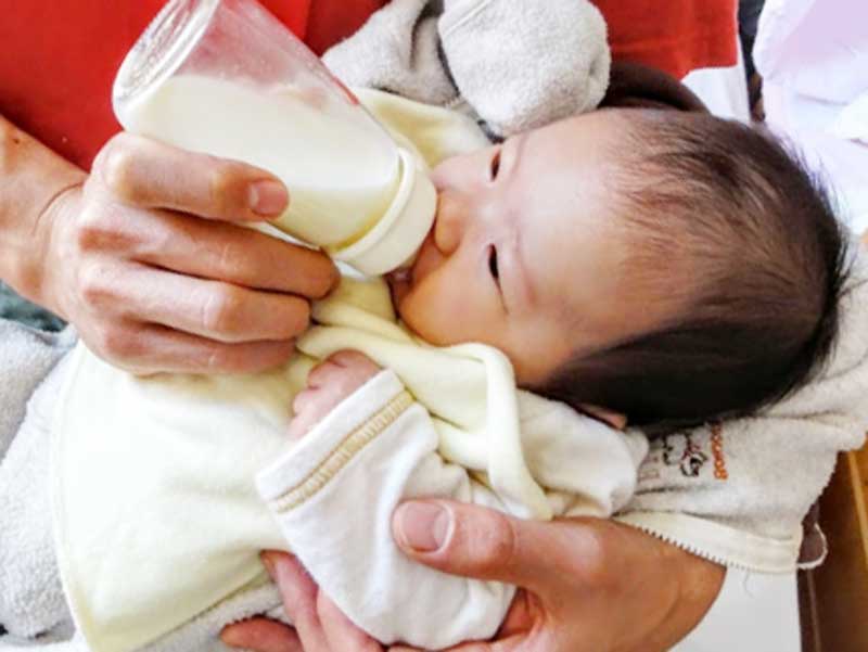 赤ちゃんにミルクを飲ませるお父さん