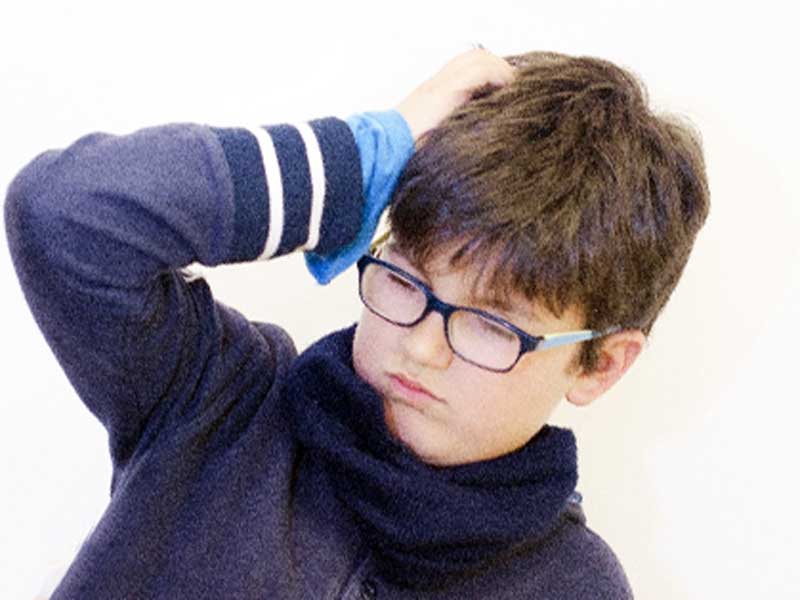 頭痛で頭をおさえている男の子