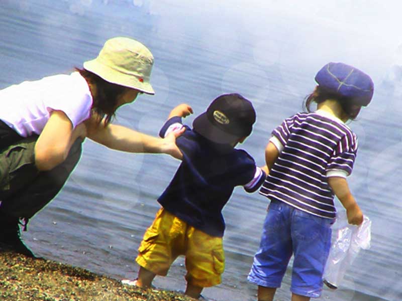 赤ちゃんと子供を連れて水遊びをしているお母さん