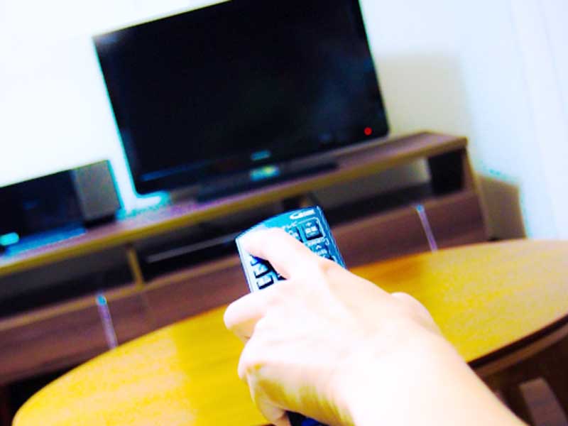 テレビのリモコンを持つ女性