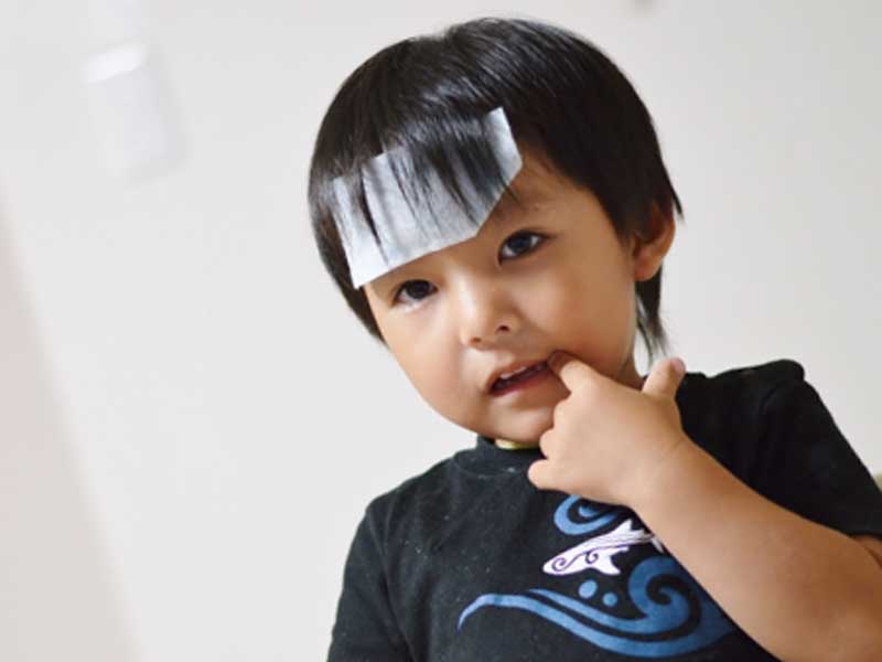 熱があって冷えピタをおでこに貼っている子供