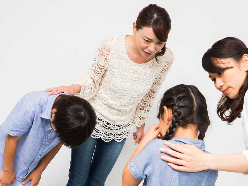 親と一緒に友達に謝っている男の子