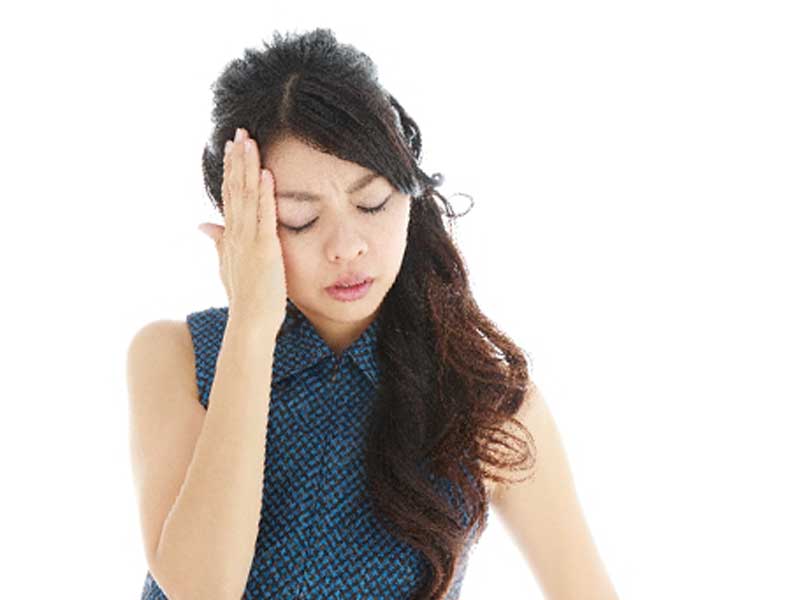 偏頭痛で頭に手をあてている妊婦さん