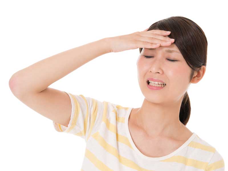 頭痛で頭をおさえている女性