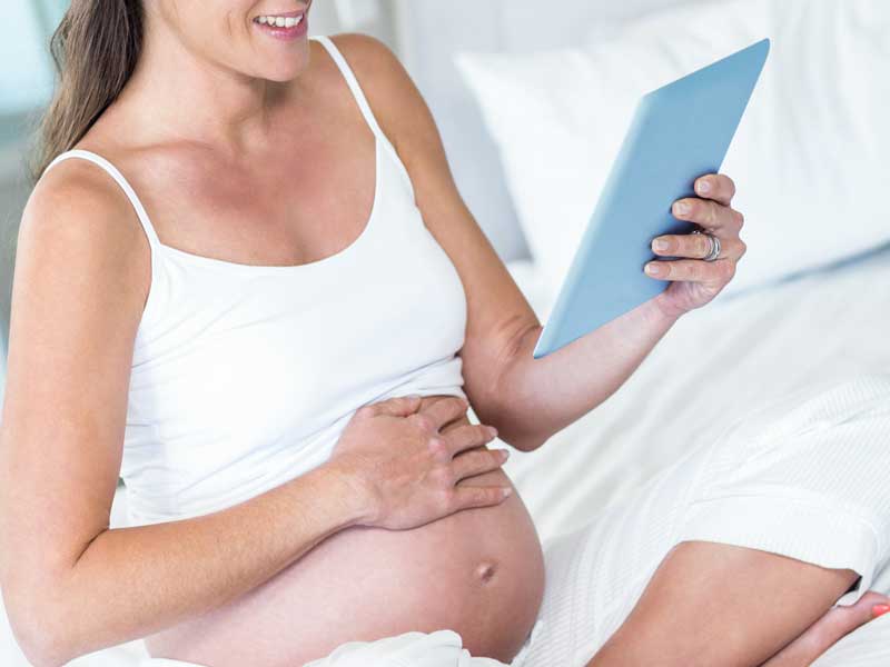 座ってお腹を触っている妊婦さん