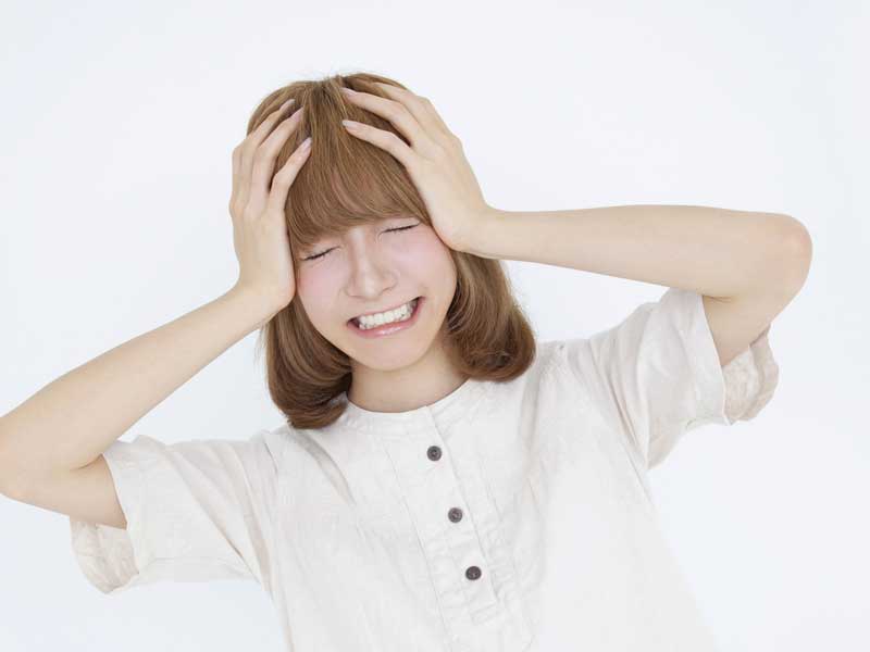 頭痛で頭をおさえているお母さん