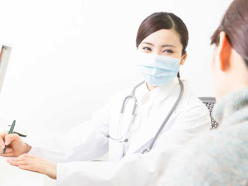 病院のかかりつけ医と相談するお母さん