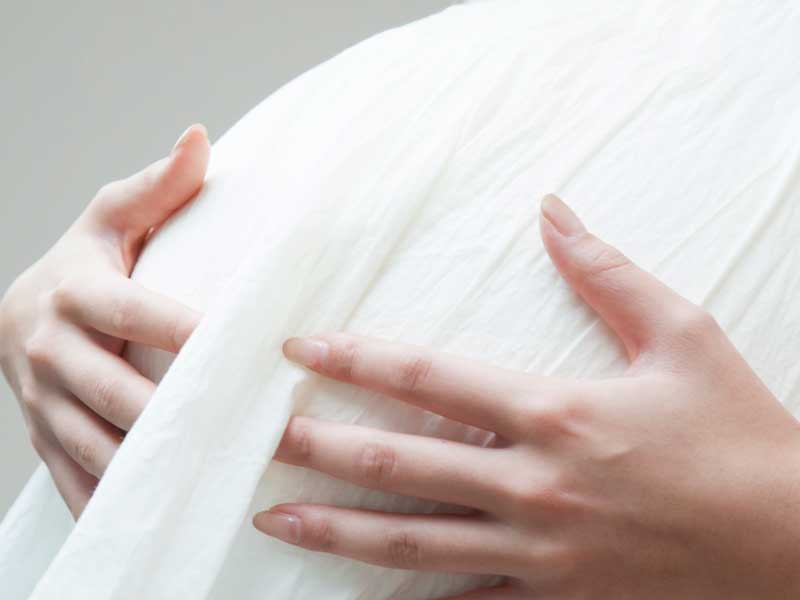 手でお腹を押さえる妊婦さん