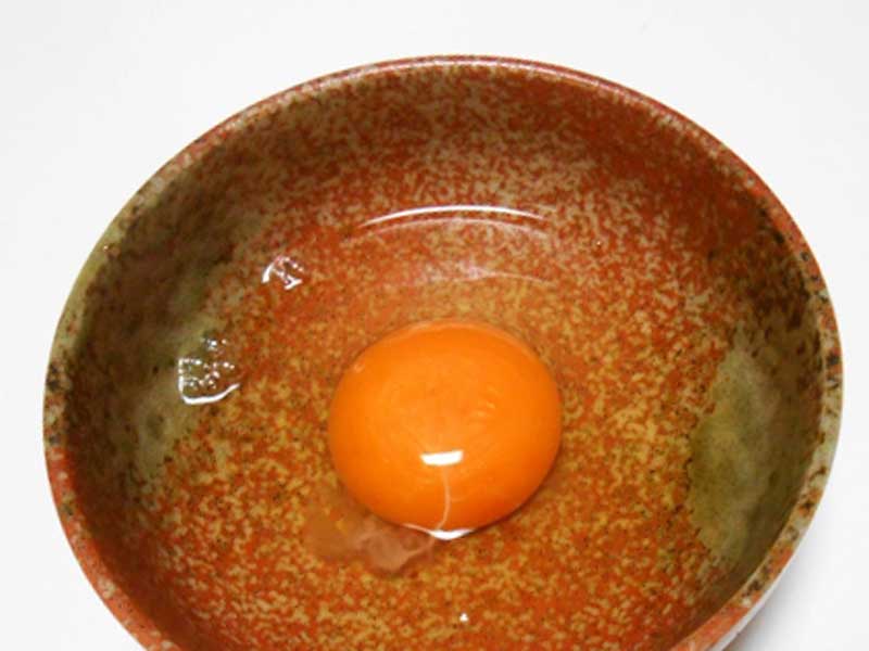 赤いお皿に入った生卵
