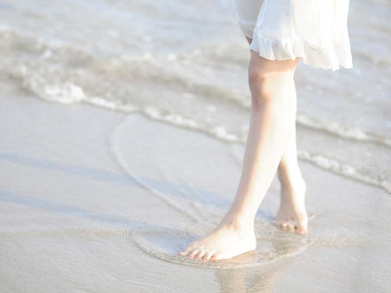 波打ち際で足だけ海に入る妊婦さん