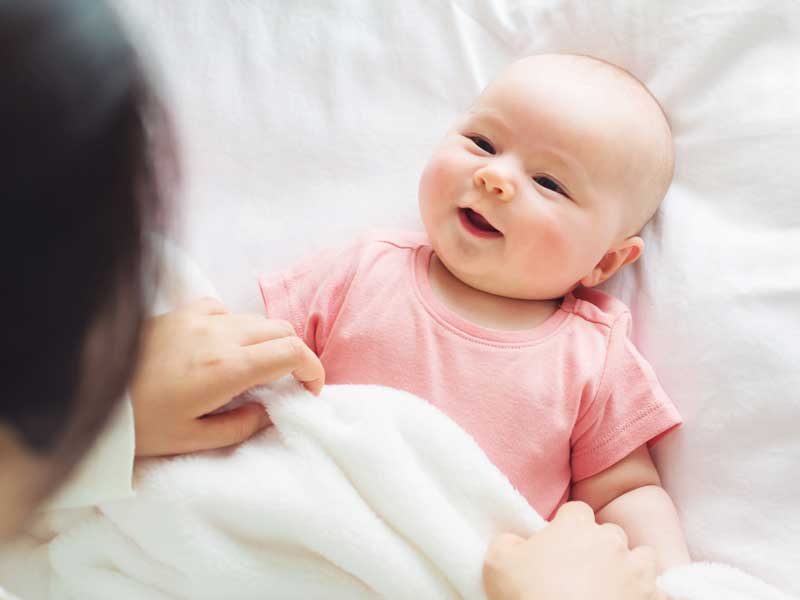 お母さんの顔を見てニコニコする赤ちゃん