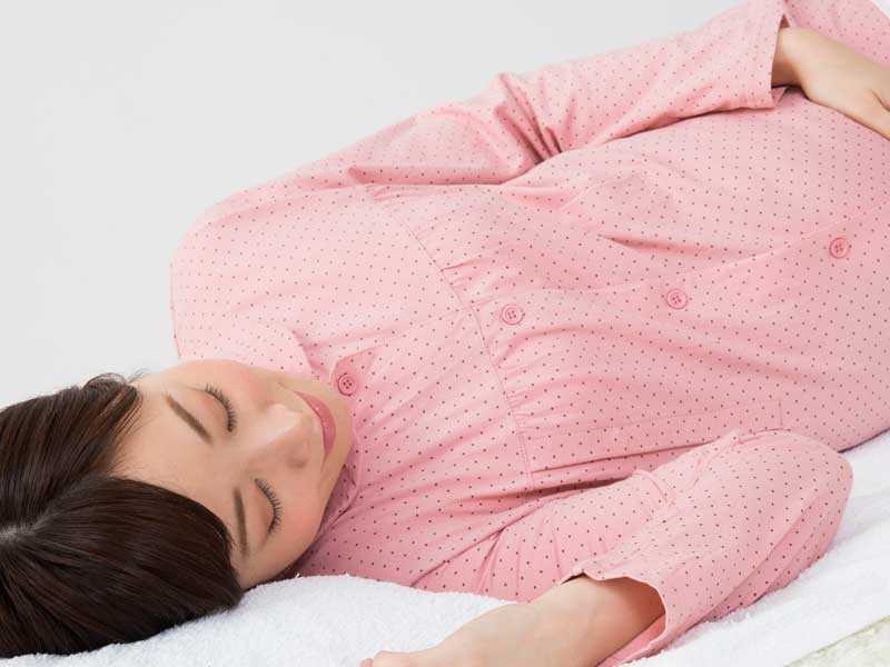 側臥で安静にしている妊婦さん