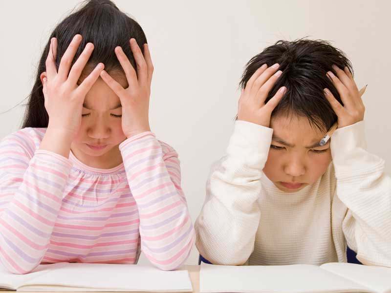 頭を抱えながら勉強している子供達