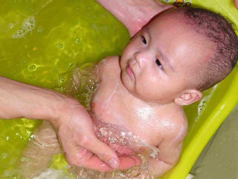 ベビーバスで沐浴をしている新生児