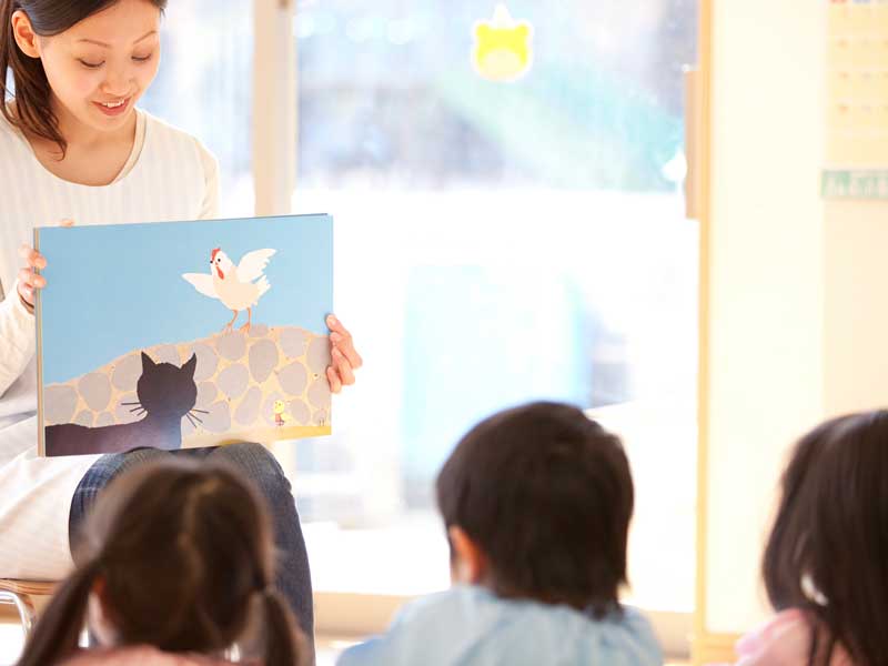 幼稚園の先生が読む絵本を聞いている園児達