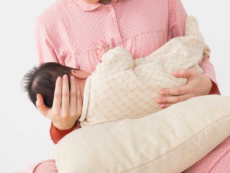 赤ちゃんを抱っこしながら授乳をしているママ