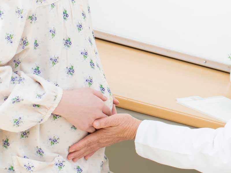 妊婦さんに腹部の触診をしている医者