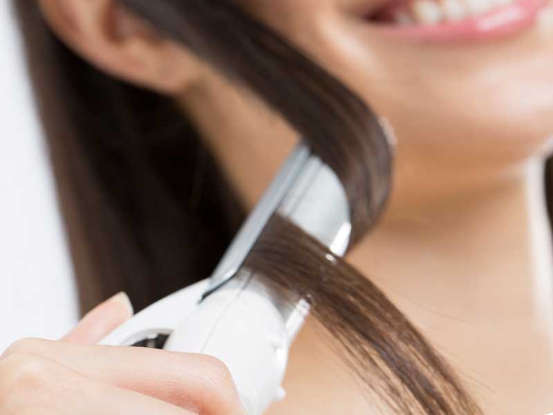 ヘアアイロンで髪を巻く女性