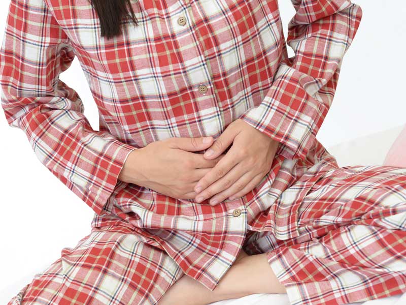 下腹部の痛みに手で抑えている女性