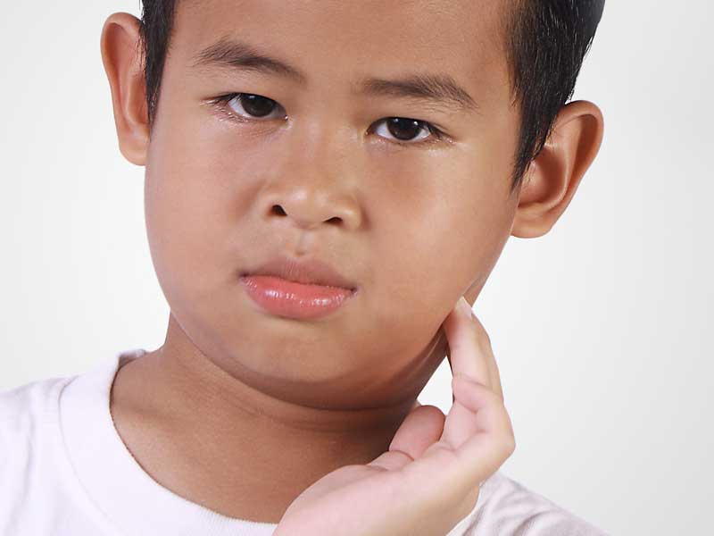 おたふく風邪で頬を手で触っている男の子