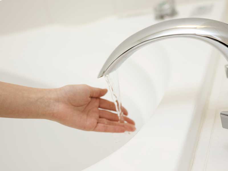 お風呂にお湯を入れている女性