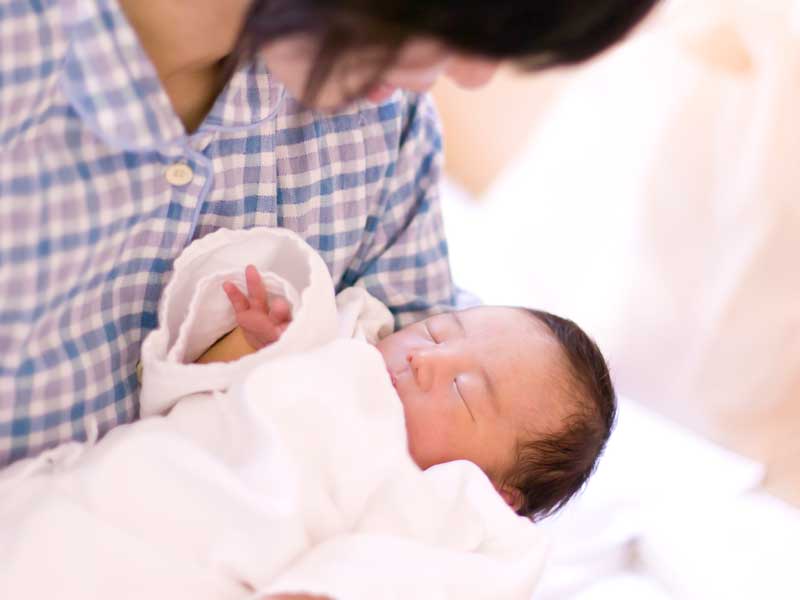 生まれたばかりの赤ちゃんを抱っこするママ