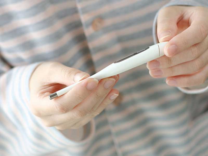 体温計で熱を測っているお母さん