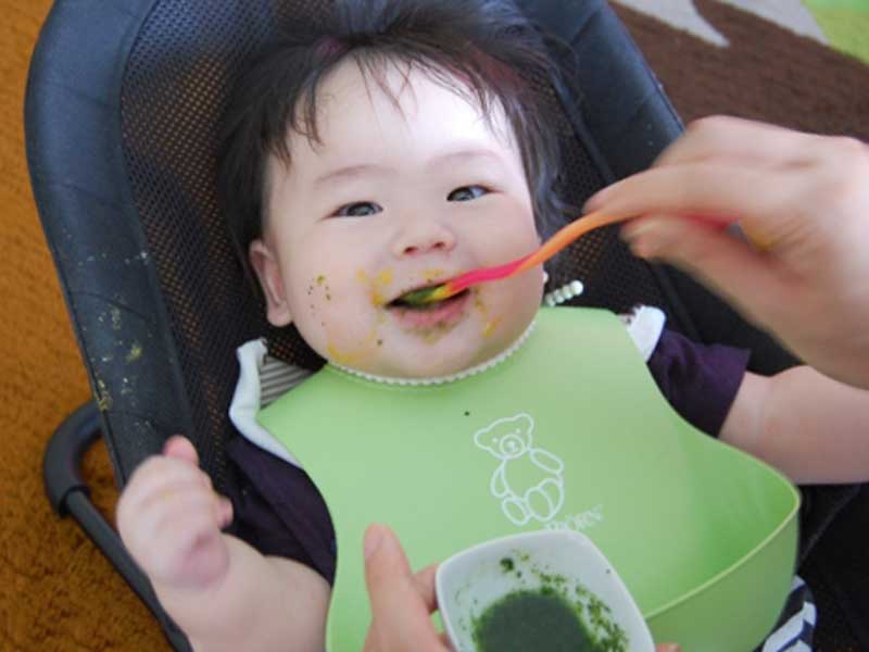 笑顔で離乳食を食べる赤ちゃん