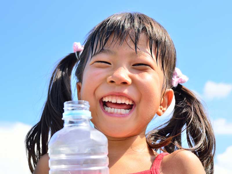 青空で水を飲む女の子