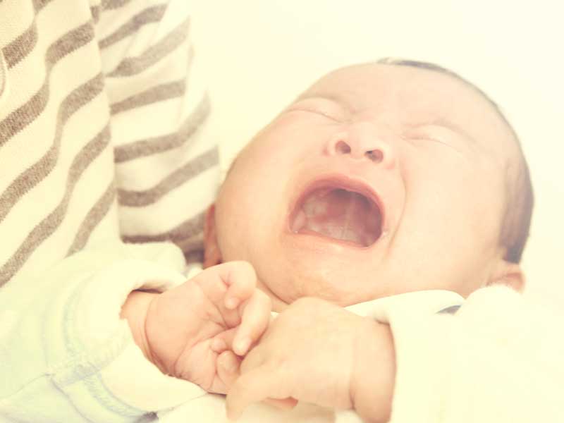 ママに抱っこされて泣いている新生児