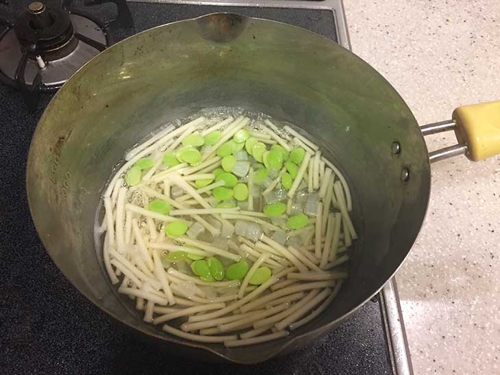 鍋でうどんと枝豆を茹でる