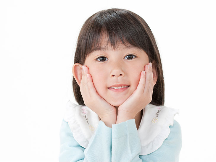 顎に両手を当てる少女