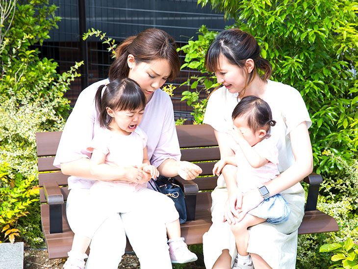 子供を抱いてベンチに座って話をしてるママ友