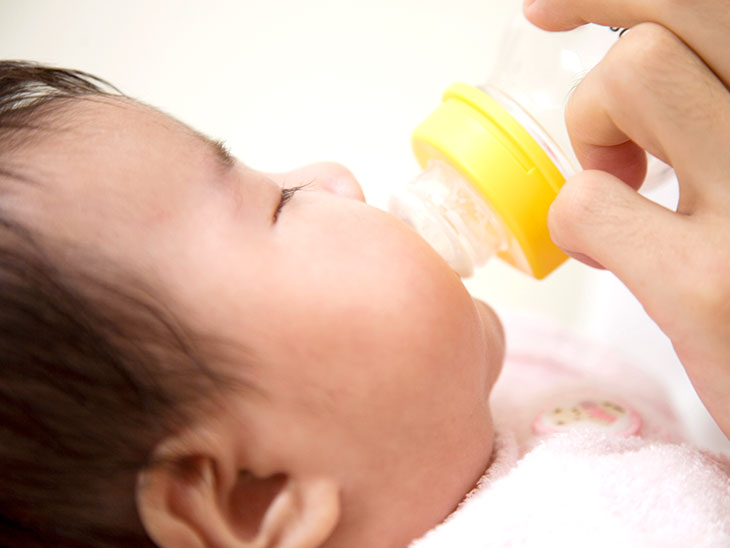 哺乳瓶からミルクを飲む女性