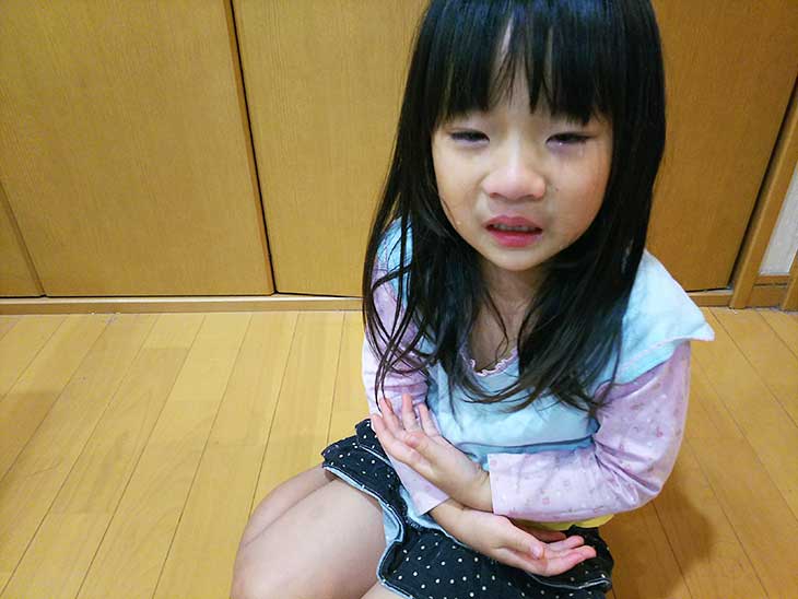 お腹を抑えて痛がっている女の子